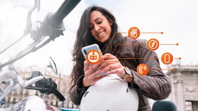 Vrouwelijke motorrijder staat naast haar motor en opent een app op haar smartphone