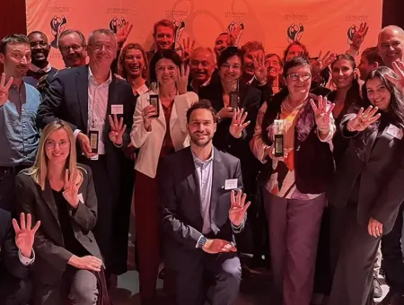 Een dertigtal collega's van P&V Groep poseren met de vier Decavi-trofeeën